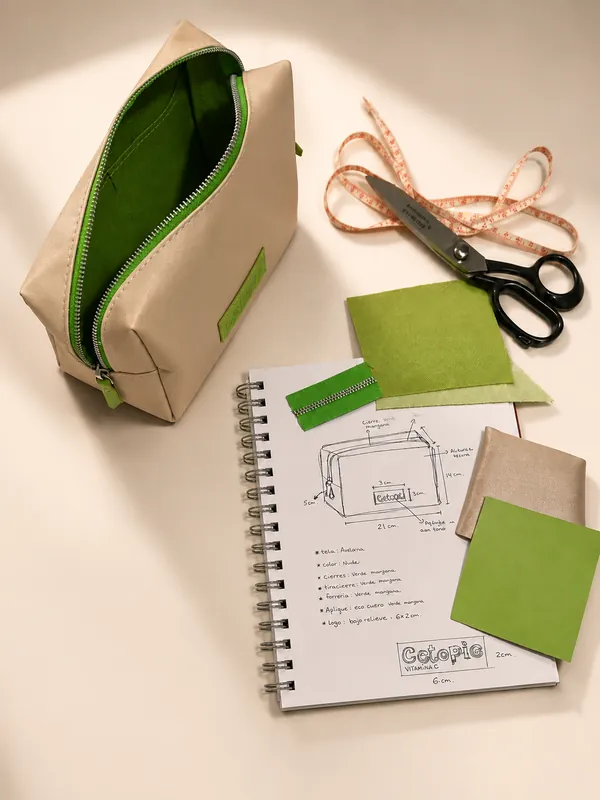 Neceser beige con cierre verde junto a bocetos de diseño de Cetopic