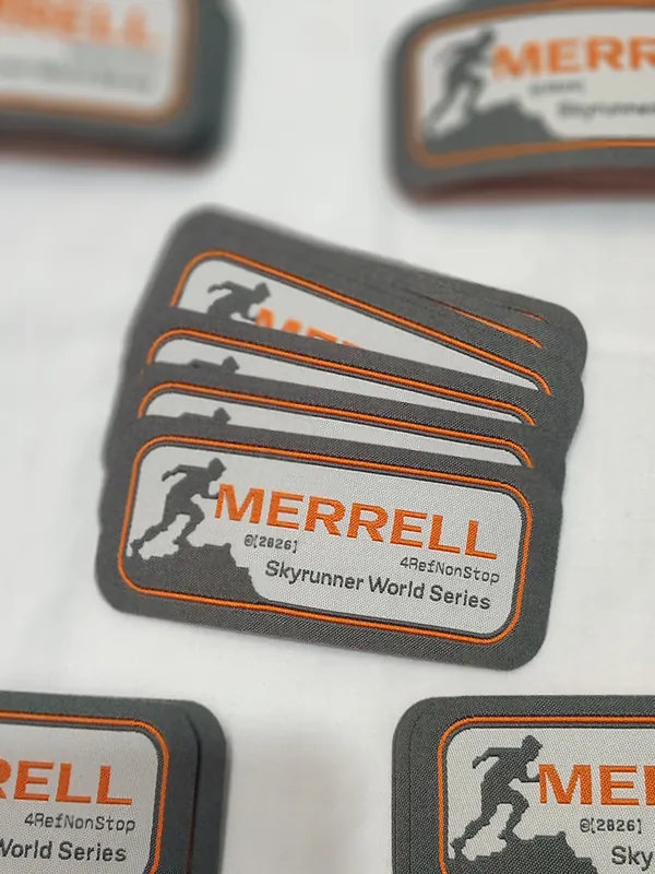 Parches bordados grises y naranjas de Merrell Skyrunner World Series apilados